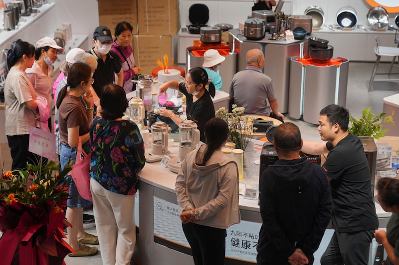 Residents gather to watch a juice mixer machine demonstration at a newly opened Chinese e-commerce platform JD.com shopping mall in Beijing, June 16, 2025.